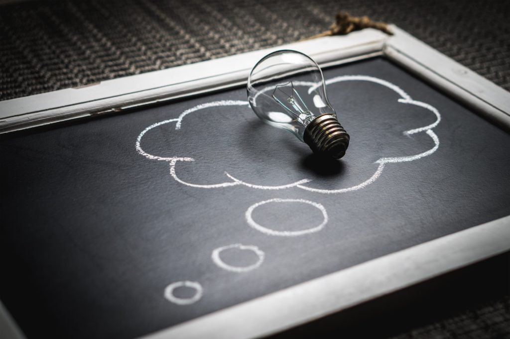 How to decide what business to start. Light bulb in a thought bubble that is drawn on a chalkboard